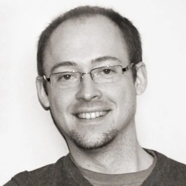Craig Hobson smiling, in glasses and a dark sweater