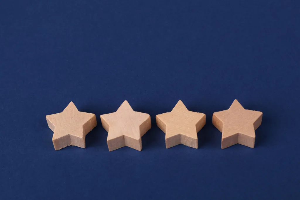 Four wooden stars in a row on a dark blue surface, a rating stuck one star short